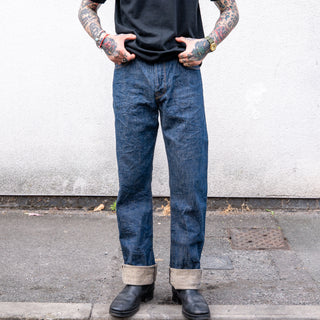 cropped image of raw denim jeans being worn with black t-shirt and leather boots