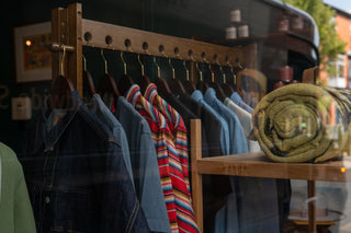 shirts hanging on rail inside the store and blanket sitting on shelf